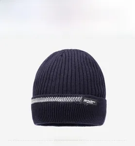 Detail of dark blue ribbed knit beanie with grey striped cuff and brand logo patch