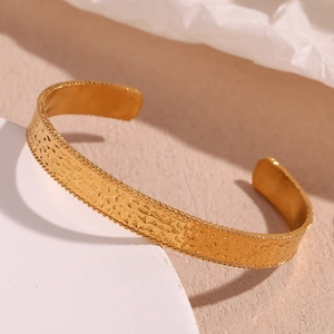 Detail of 18K gold-plated open cuff bracelet with hammered texture and twisted rope edges