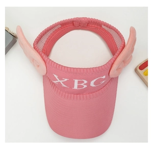 Detail of pink knitted sun visor for kids featuring 3D wings and XBG jacquard logo