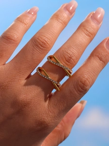 Close-up of gold double-layered crisscross ring with zircons worn on model finger