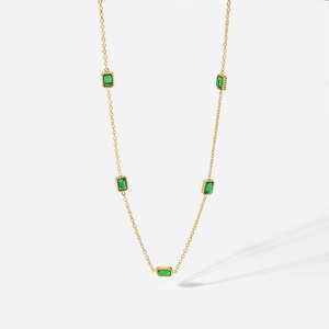 Collier en acier titane doré avec cinq pierres de zircone vert émeraude sur fond blanc