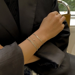 Close-up of three layered silver snake and curb chains on a model wearing a black blazer