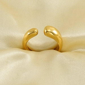 Bague ouverte élégante en acier inoxydable doré 18 carats sur un tissu en soie dorée