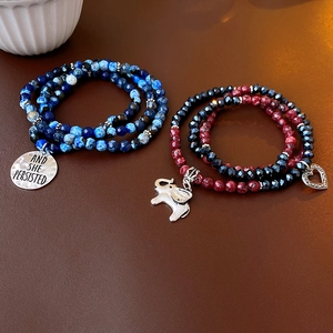 Detail of beaded bracelets featuring blue marble beads and an engraved round pendant