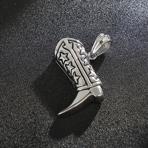 Detail of silver cowboy boot pendant with star relief on black textured background