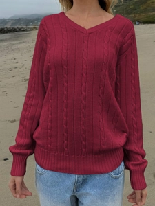 Detailed cable knit texture and V-neckline on a dark red women's sweater shown outdoors