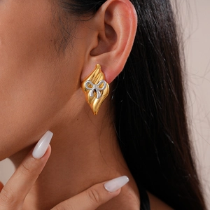 Gros plan de boucles d'oreilles losanges avec nœud argenté porté par un modèle