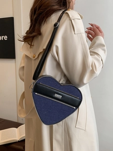 Blue denim heart shaped crossbody bag with black leather trim and silver zipper closure