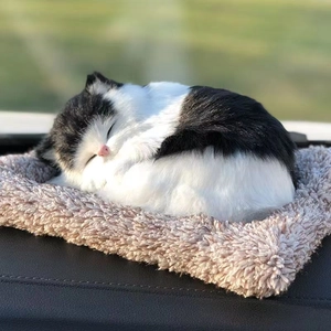 Close-up of a lifelike black and white plush cat sleeping on a soft fuzzy cushion