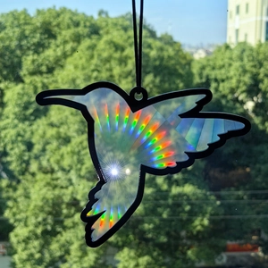 Detail of hummingbird suncatcher with holographic light refraction effect on a window