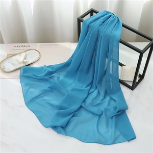 Detail of teal chiffon scarf draped on a metal frame showing soft semi-transparent texture