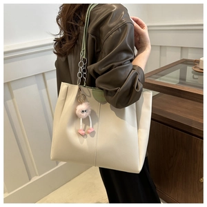 Vista dettagliata della borsa tote in pelle crema con tracolla a catena e ciondolo