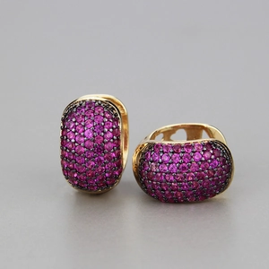Gold huggie earrings with pave pink zircons and black rhodium finish on gray background