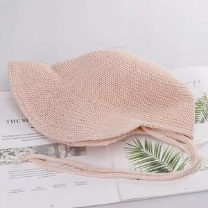 Detail of pink knit sun hat with wavy brim and chin ties on a vintage magazine
