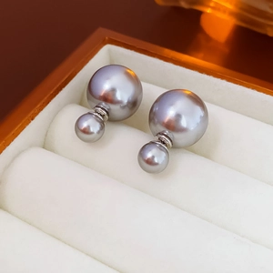 Detailed close-up of double pearl earrings in a luxury jewelry box with silver finish