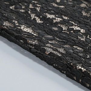 Dettaglio del pizzo nero con motivi floreali traforati e trama del tessuto di alta qualità
