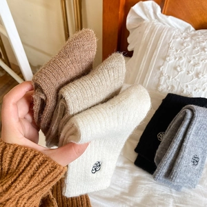 Close-up of thick knitted winter socks with delicate flower embroidery in soft lighting