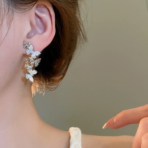 Detail of silver butterfly tassel earrings with zircon and mother-of-pearl on a model