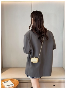 Detail of a luxury mini gold metallic suitcase-style crossbody bag with vertical texture