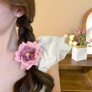 Detail of pink fabric rose hair clip showing layers of petals on side braided hairstyle