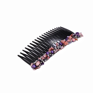 Detail of black plastic hair comb featuring purple and pink stones and white pearl beads