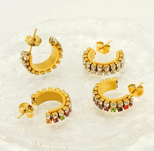 Macro view of C-shaped gold-plated hoop earrings with sparkling white and rainbow zirconias