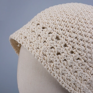 Detailed close-up of handmade hollow-out crochet knit pattern on a beige summer bucket hat