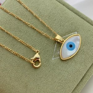 Golden Figaro chain necklace with oval Mother of Pearl Evil Eye pendant on green fabric