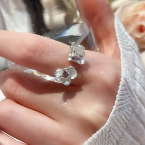 Detailed view of silver orchid ring with purple stones and brushed texture on fingers