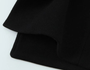 Close-up of black woolen coat fabric showing heavy texture and quality stitching details