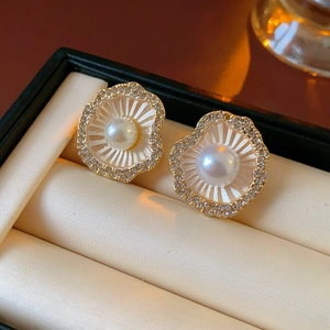 Gros plan de boucles d'oreilles fleur en perles dorées dans un écrin en velours beige