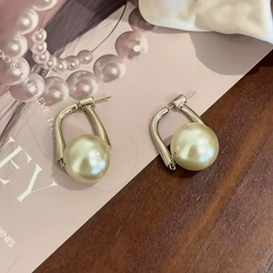Elegant minimalist faux pearl earrings with gold hooks on vintage wooden table