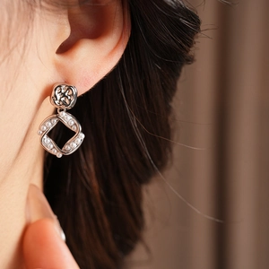 Close-up of a silver-plated square earring with twisted frame and white pearl accents