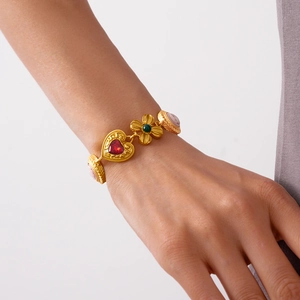Vintage gold metal bracelet with heart, flower, and portrait charms on a female wrist
