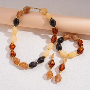 Detail view of ethnic acrylic beaded jewelry set with faceted amber and black beads