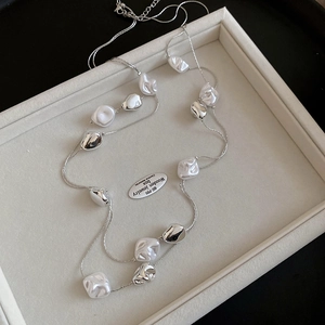 Detail of vintage silver chain necklace with irregular pearls on a jewelry tray