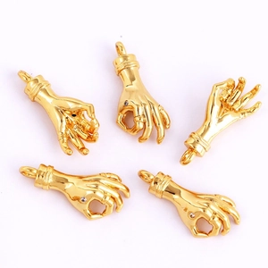 Macro detail of gold-plated copper hand-shaped charms with polished finish for jewelry