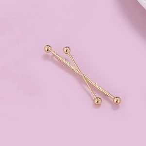 Macro view of gold-plated industrial piercing bars with smooth metallic spherical ends