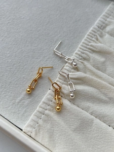 Detail view of gold and silver S925 sterling silver horseshoe ball earrings on jewelry tray