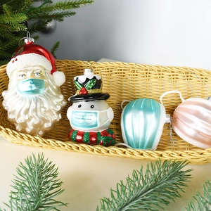 Set of 4 glass Christmas ornaments featuring Santa and snowman with face masks in a basket