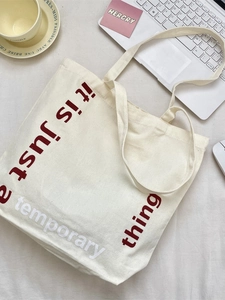 Grand sac cabas en toile beige avec texte bordeaux dans un décor de style de vie