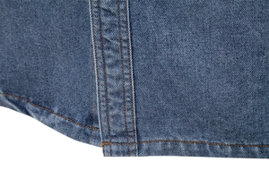 Gros plan sur la double couture de l'ourlet d'une chemise en jean bleu délavé