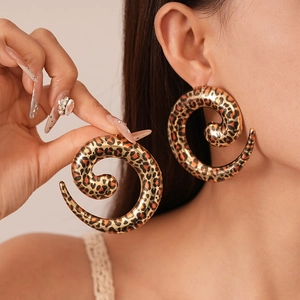 Close-up of oversized spiral leopard print earrings with a polished golden finish