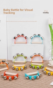 Macro detail of ergonomic wooden handle and colorful metal bells for baby hand rattles