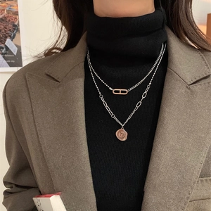 Détail du collier double couche argenté avec anneau ovale et pendentif pièce de monnaie