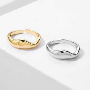 Close-up of minimalist gold and silver wavy rings with a polished mirror finish