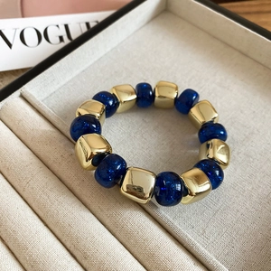 Close-up of luxury elastic bracelet with gold square beads and blue glitter acrylic beads
