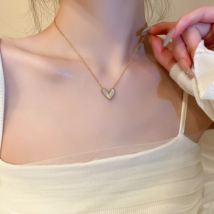 Detail shot of a minimalist gold heart pendant necklace with white shell inlay on a model