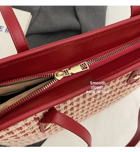 Close-up of the smooth gold-tone zipper and red leather trim on the tweed tote bag