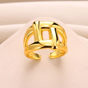 Detailed close-up of a gold-plated geometric knot ring on a pink textured surface